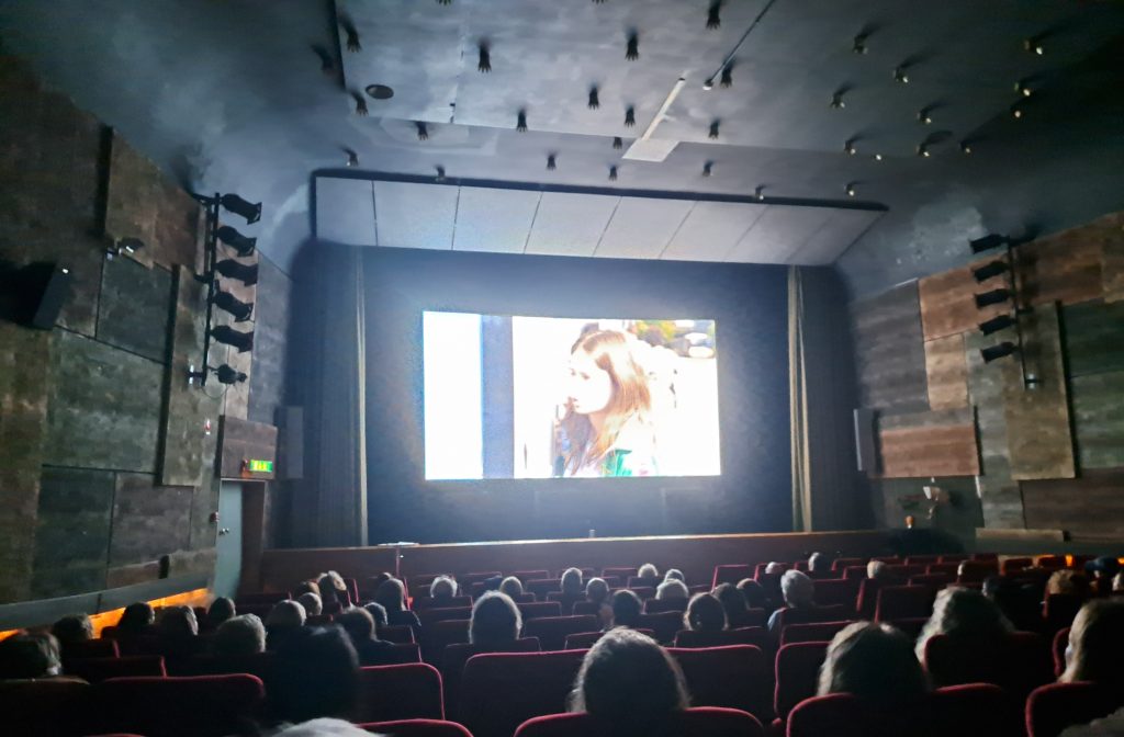 En publik sitter i en biograf och tittar på en film på duken.